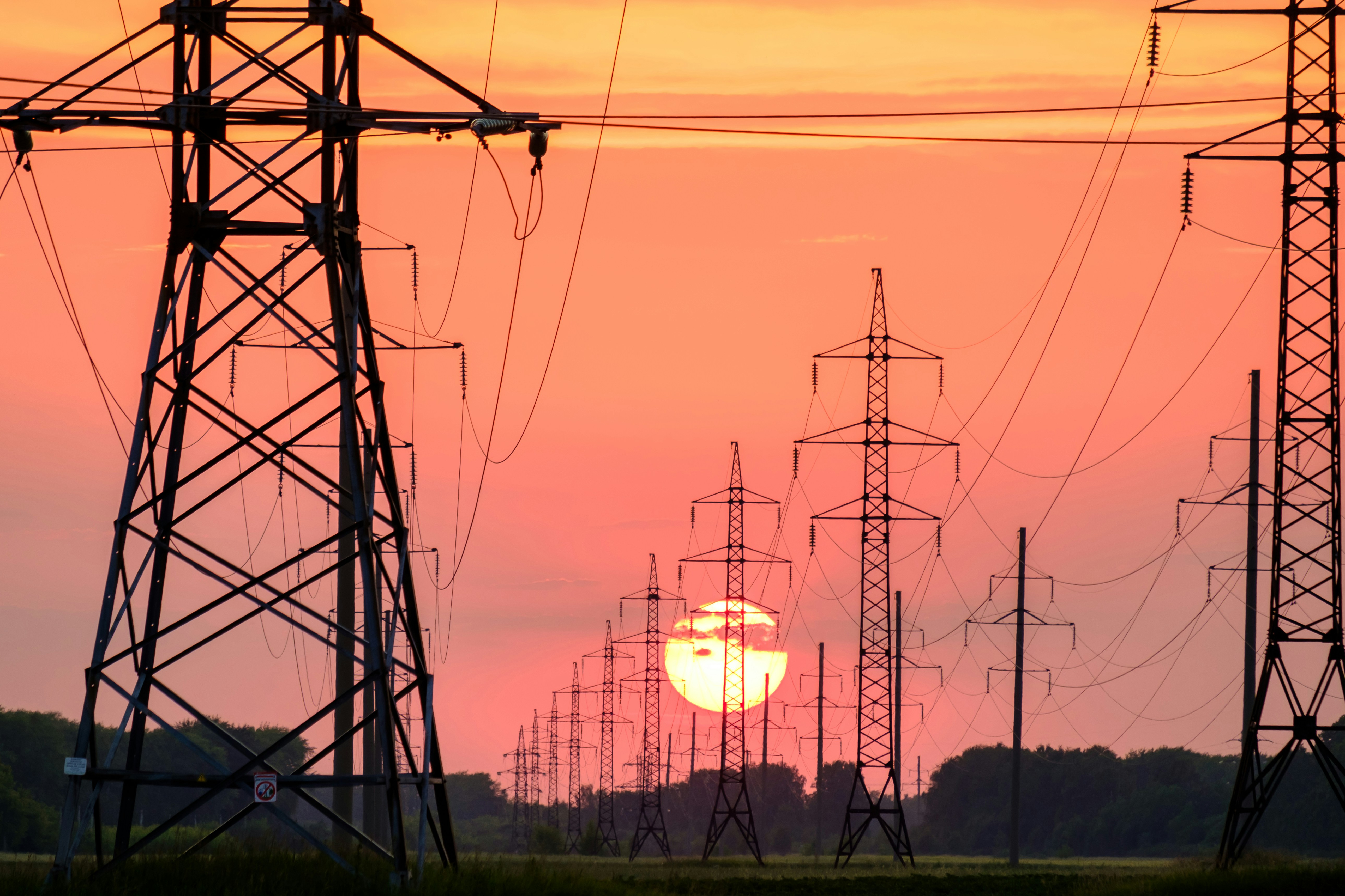 Transmission towers and power lines at sunset